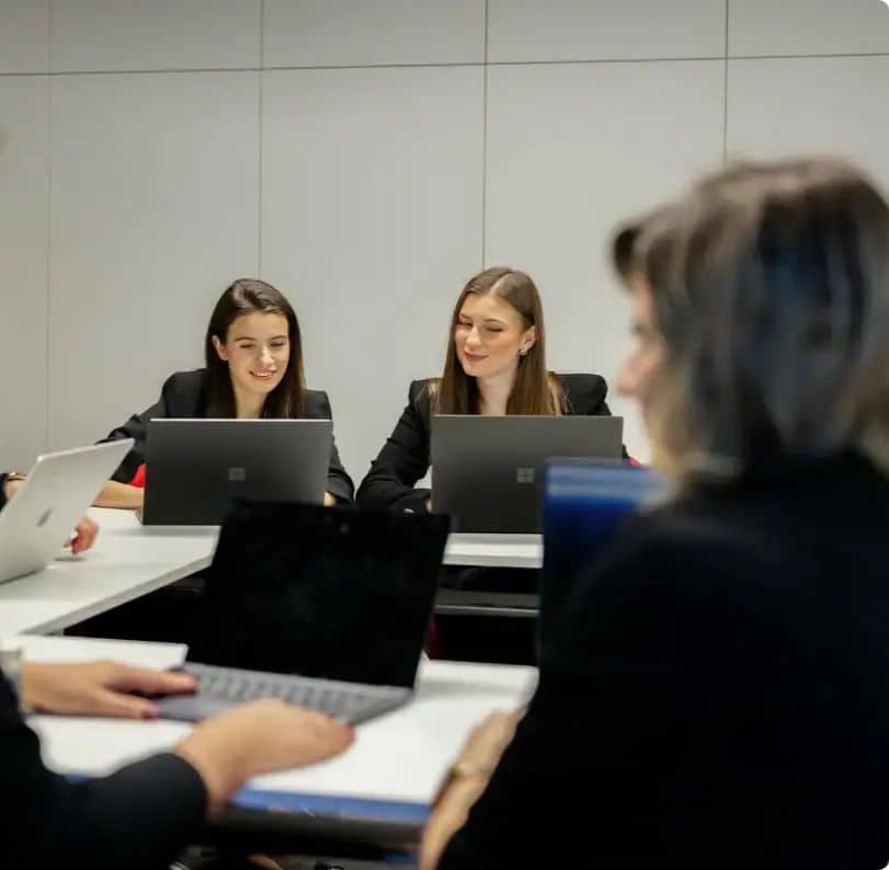 Dwie studentki pracują przy komputerze z uśmiechem